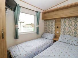 A bedroom with two single beds blue patterned bedding a wooden headboard and a window with teal curtains at 75 Foxburrow Hang in Fritton
