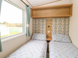 A bedroom with two single beds and a window with curtains at 75 Foxburrow Hang in Fritton