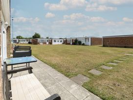 An outdoor space with grass, chairs, and tables near buildings at 440 California Sands