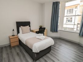 A bedroom with a bed, nightstand, desk and chair at The Newborough Apartment 2 in Scarborough