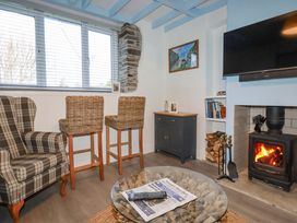 A living room with bar stools and a wood stove at Puffin Cottage in Tintagel