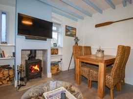 A dining room with a television and a fireplace at Puffin Cottage in Tintagel