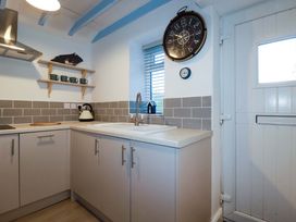 A kitchen with cabinets, sink, and kettle at Puffin Cottage in Tintagel