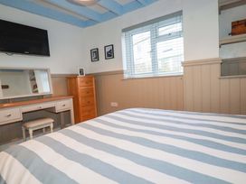 A bedroom with a bed and dresser at Puffin Cottage in Tintagel