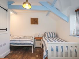 A bedroom with two beds and a side table at Puffin Cottage in Tintagel