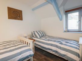 A bedroom with two single beds and a window at Puffin Cottage in Tintagel