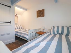 A bedroom with two striped beds at Puffin Cottage in Tintagel