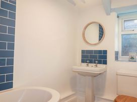 A bathroom with a bathtub, sink, mirror and window at Puffin Cottage in Tintagel