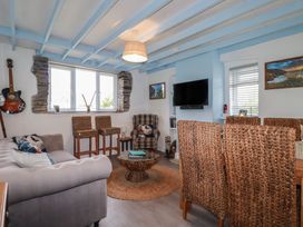 A living room with a guitar and a television at Puffin Cottage in Tintagel