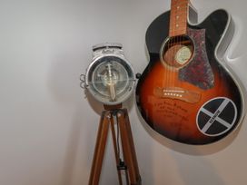 A guitar and a lamp on a wooden tripod at Puffin Cottage in Tintagel