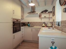 A kitchen with cabinets and appliances at Puffin Cottage in Tintagel