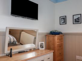 A bedroom with a television and a mirror at Puffin Cottage in Tintagel