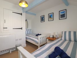 A bedroom with two beds and a bedside table at Puffin Cottage in Tintagel