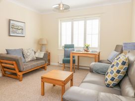 A living room with two sofas a wooden coffee table and a small dining table with chairs at Malting Cottage in Dawlish