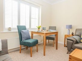 A dining area with a wooden table and two chairs next to a window in a living room at Malting Cottage in Dawlish
