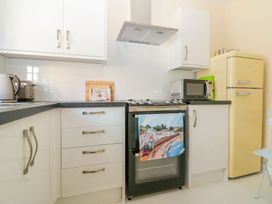 A kitchen with white cabinets a stove with a towel a microwave a yellow refrigerator and countertop appliances at Malting Cottage in Dawlish