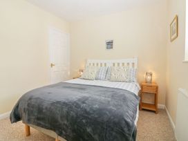 A bedroom with a double bed two bedside tables and lamps at Malting Cottage in Dawlish