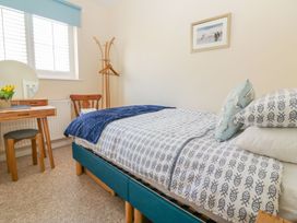 A bedroom with a single bed a wooden chair a dressing table and a coat rack at Malting Cottage in Dawlish