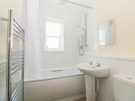 A bathroom with a bathtub shower combination sink toilet towel rail and a window at Malting Cottage in Dawlish