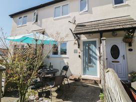 Outdoor seating area with table umbrellas and chairs outside a two story house with blue and white doors at Malting Cottage in Dawlish