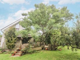 A garden with a tree, house, deck, and chairs at 6 The Links Praa Sands