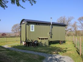 A green corrugated metal shepherds hut with black roof and wheels on a grass field at Gilberry Shepherds Hut in Wall under Heywood near Church Stretton