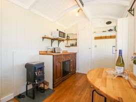 A small kitchen area with a wood stove microwave and wooden dining table at Gilberry Shepherds Hut Wall under Heywood near Church Stretton