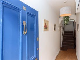 A hallway with a blue door numbered 16 pictures on the wall stairs at Harbour Hideaway in Dartmouth