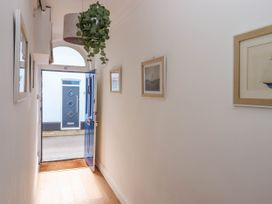 A hallway with wooden floor pictures on walls and a blue door open to the outside at Harbour Hideaway in Dartmouth