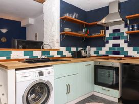 A kitchen with a washing machine oven sink toaster and shelves at Harbour Hideaway in Dartmouth