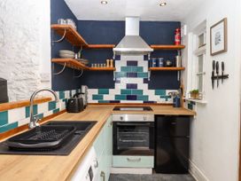 A kitchen with black sink and drying rack wooden countertop and tiled backsplash at Harbour Hideaway in Dartmouth