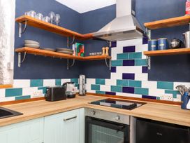 A kitchen corner with wooden shelves holding dishes glasses and containers and a stove with an oven below at Harbour Hideaway in Dartmouth