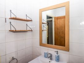 A bathroom with a wooden framed mirror wooden shelves a sink and blue patterned soap dispenser at Harbour Hideaway Dartmouth