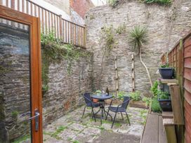 A small stone courtyard with a round table and two chairs surrounded by stone walls and plants at Harbour Hideaway in Dartmouth