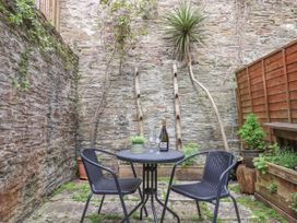 A small outdoor patio with a round table two chairs plants and stone walls at Harbour Hideaway in Dartmouth