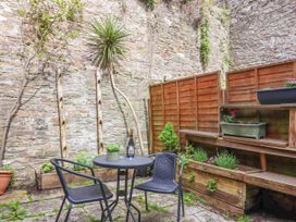 A small outdoor patio with a round table and two chairs plants on shelves and stone walls at Harbour Hideaway in Dartmouth