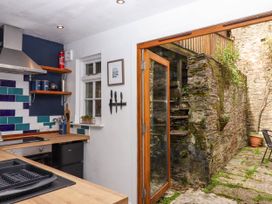 A kitchen with wooden counters and tiled backsplash opening to a stone-walled outdoor patio with stairs at Harbour Hideaway in Dartmouth