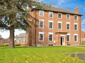 A three story brick building with multiple windows and a door in a grassy area with trees at Holmer House Farm in Holmer near Hereford