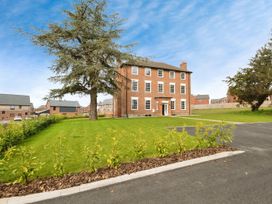 A three-story brick building with multiple windows and a front door with pathways and trees at Holmer House Farm in Holmer near Hereford