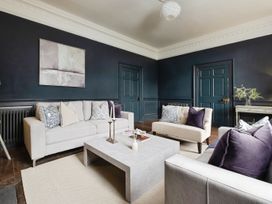 A living room with beige sofas purple and patterned cushions a stone coffee table and dark blue walls at Holmer House Farm in Holmer near Hereford