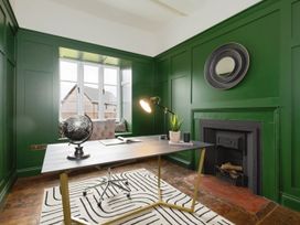 An office room with a desk lamp globe and plant on the desk a fireplace and green panelled walls at Holmer House Farm Holmer near Hereford