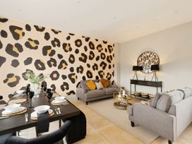 A living room and dining area with patterned wall and grey sofas at Holmer House Farm in Holmer near Hereford