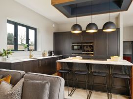 A kitchen with dark cabinets an island with bar stools and pendant lights at Holmer House Farm in Holmer near Hereford