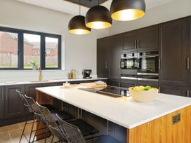 A kitchen with a large island with stools and pendant lights at Holmer House Farm in Holmer near Hereford