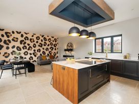 A kitchen with an island and three hanging lights next to a dining area and a living space with a patterned wall at Holmer House Farm in Holmer near Hereford