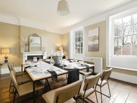 A dining room with a table set for eight people near windows and a fireplace at Holmer House Farm in Holmer near Hereford