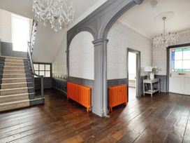 A hallway with wooden floors two chandeliers a staircase with carpet and orange radiators at Holmer House Farm Holmer near Hereford