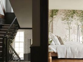 A staircase with carpeted steps and a window next to a bedroom with a bed and tree patterned wallpaper at Holmer House Farm in Holmer near Hereford