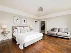 A bedroom with a double bed two bedside tables with lamps a gray sofa and wooden flooring at Holmer House Farm in Holmer near Hereford