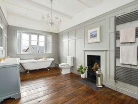 A bathroom with a freestanding bathtub next to a window a toilet a fireplace with logs a towel rack and a vanity unit at Holmer House Farm in Holmer near Hereford